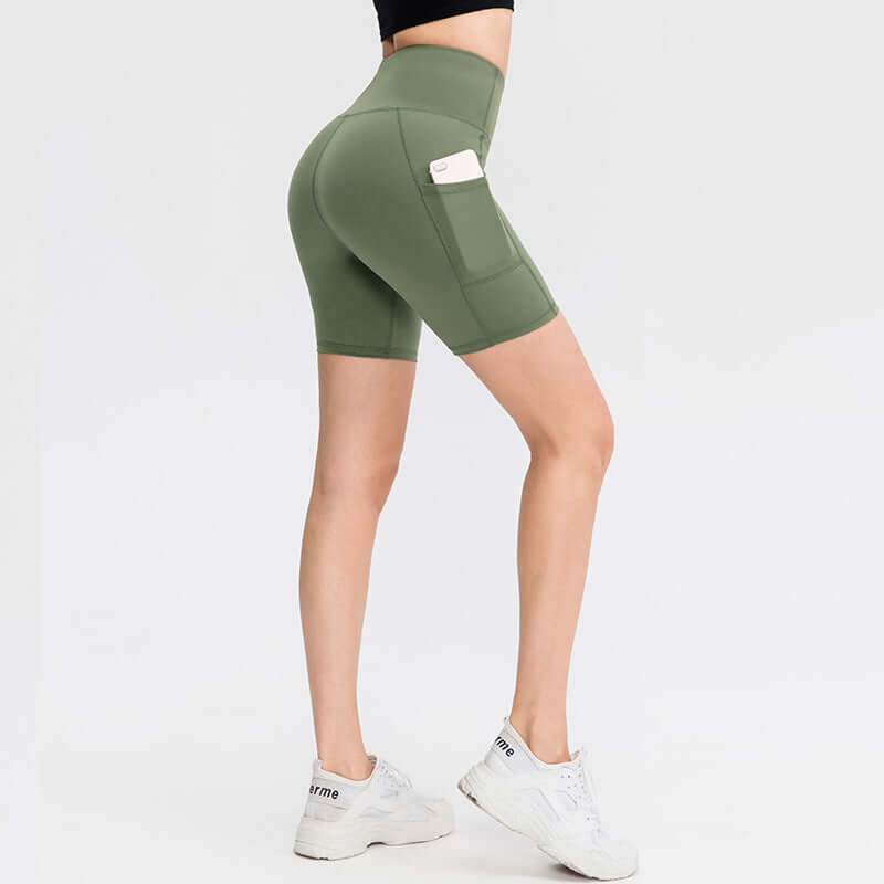 Woman wearing green pocket sport shorts with side pocket for exercise, paired with white sneakers