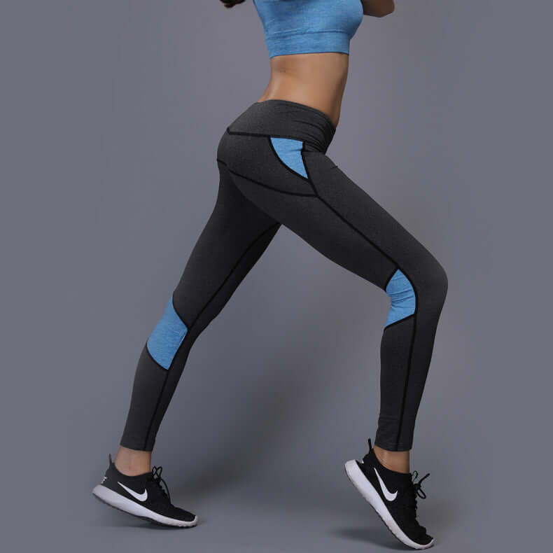 Side view of athletic mesh panel leggings in gray and blue, made of polyester fiber, shown on a model in a running pose for fitness wear.