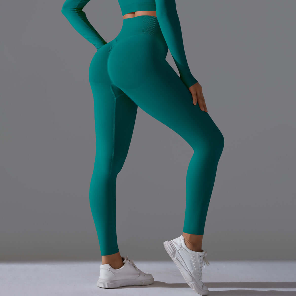 Woman wearing seamless high waist leggings in teal, showcasing back view with athletic fit and white sneakers.