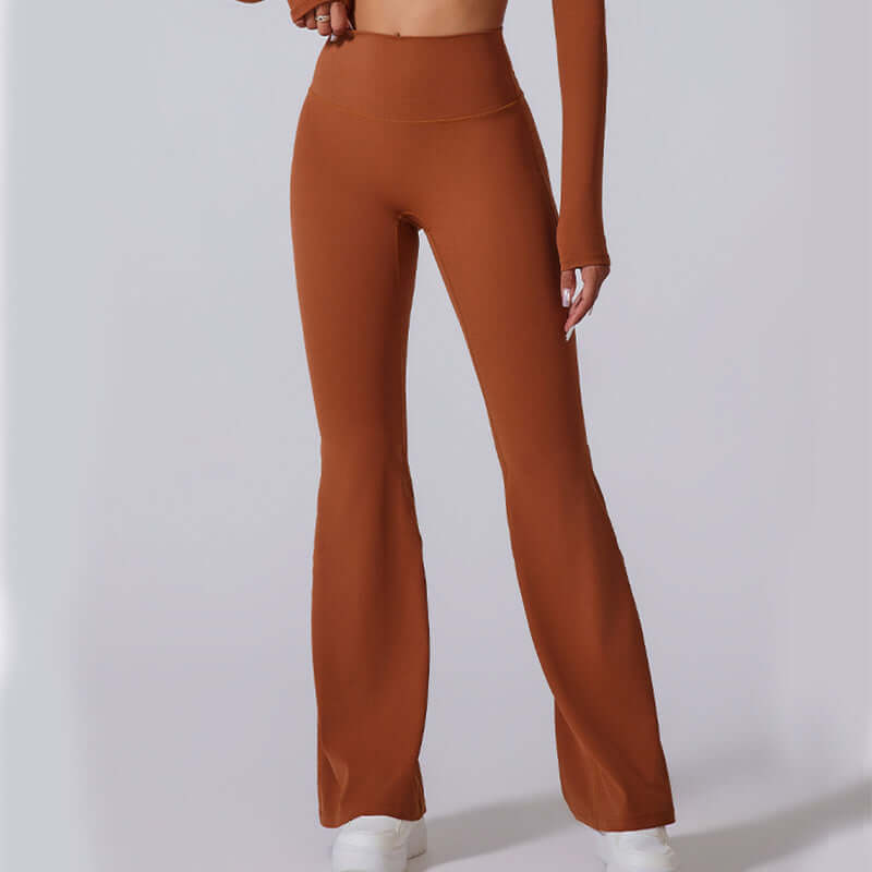 Woman wearing brown high-waisted flared yoga pants with white sneakers, showcasing flexible fit ideal for exercise and casual wear.