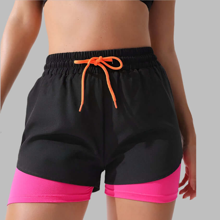 Woman wearing anti-exposure drawstring sports shorts in black and pink for active workouts.
