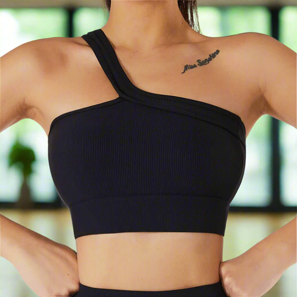 Woman wearing an advanced black one-shoulder asymmetric sport bra made of breathable nylon and spandex, ideal for fitness activities.