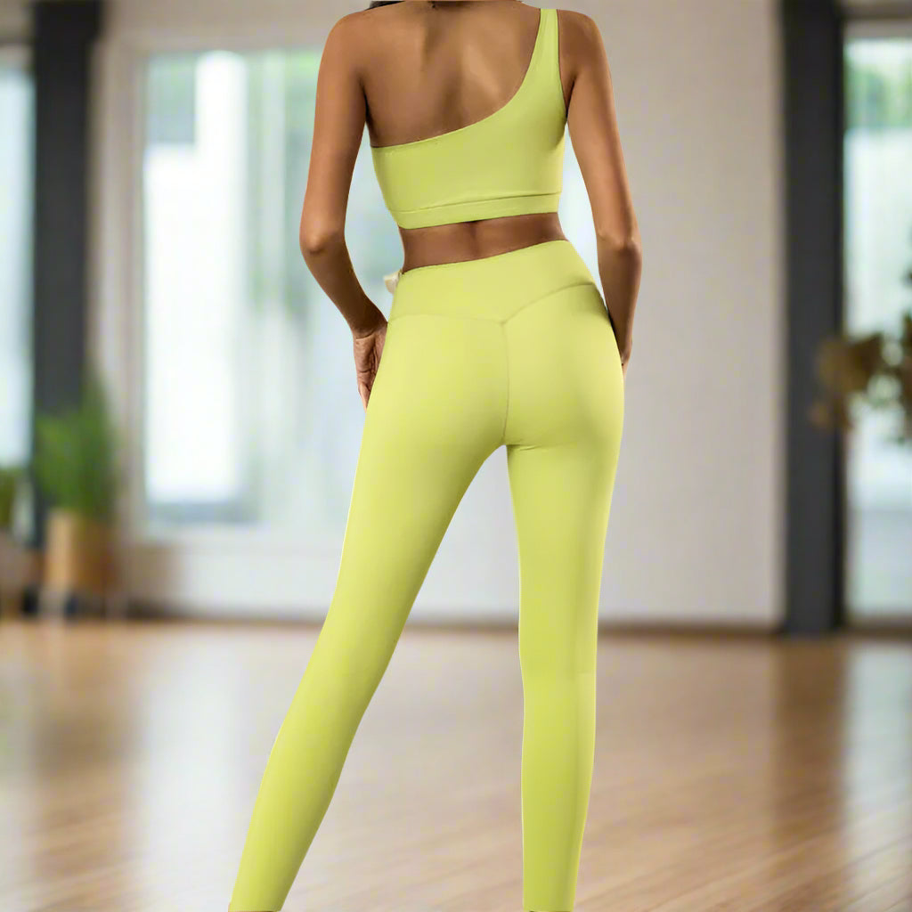 Woman wearing high elastic one-shoulder tank and leggings set in lime green, rear view