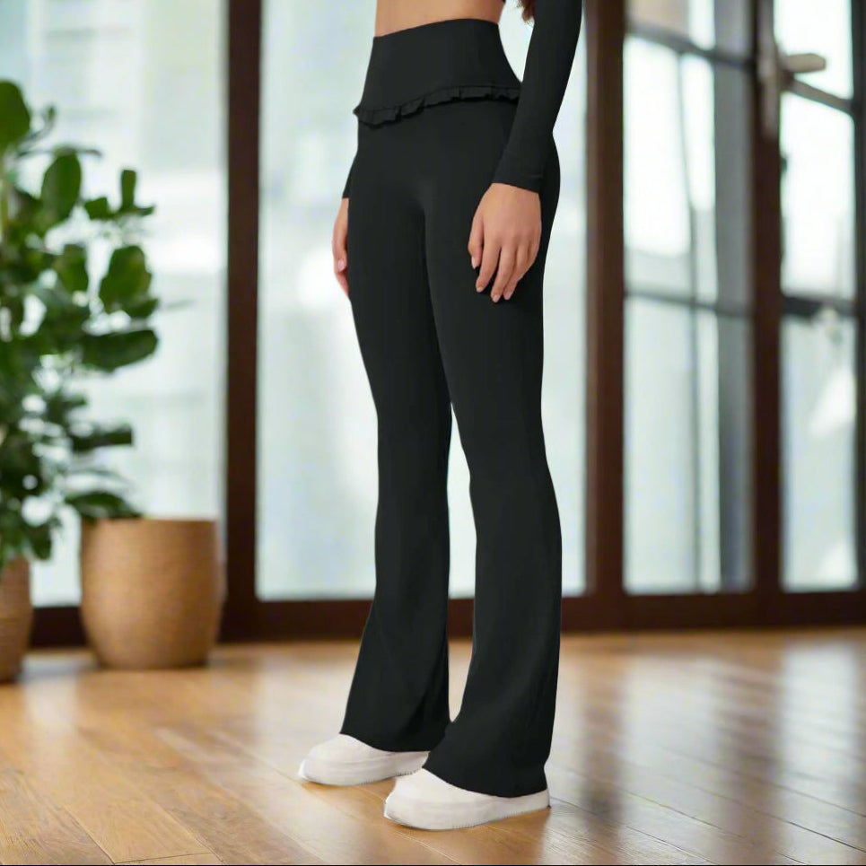 Woman wearing high waist black leggings with flared legs and comfortable fit, side view on a gray background.