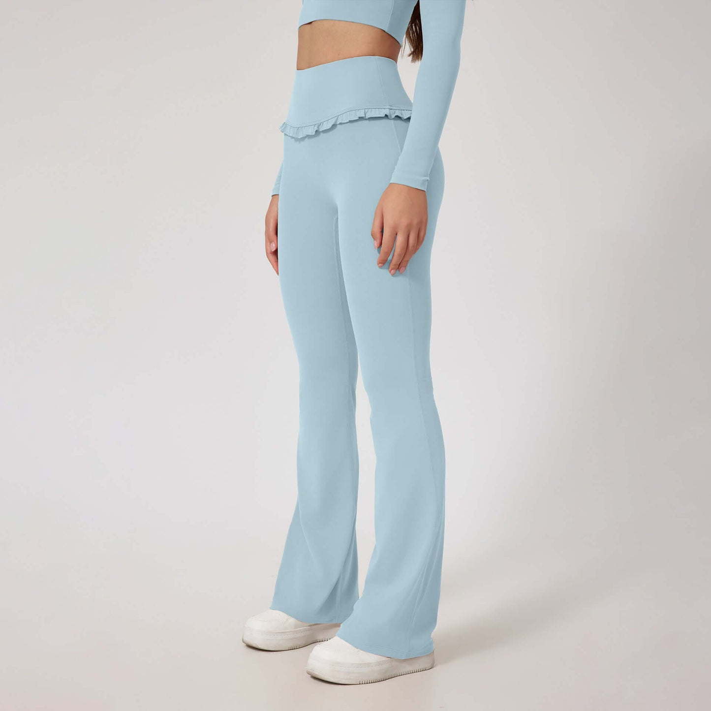 Woman wearing high waist blue leggings and matching top with white sneakers.