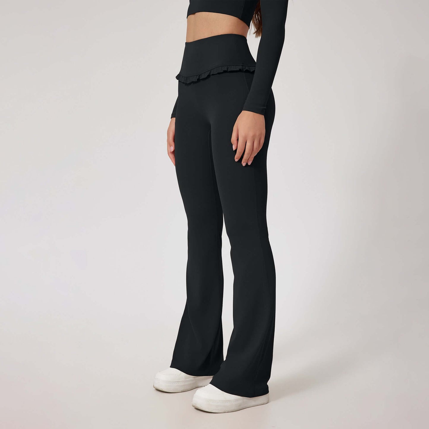 Woman wearing black high waist leggings with flared legs and white shoes, showcasing a stylish and comfortable look for workouts or casual wear.