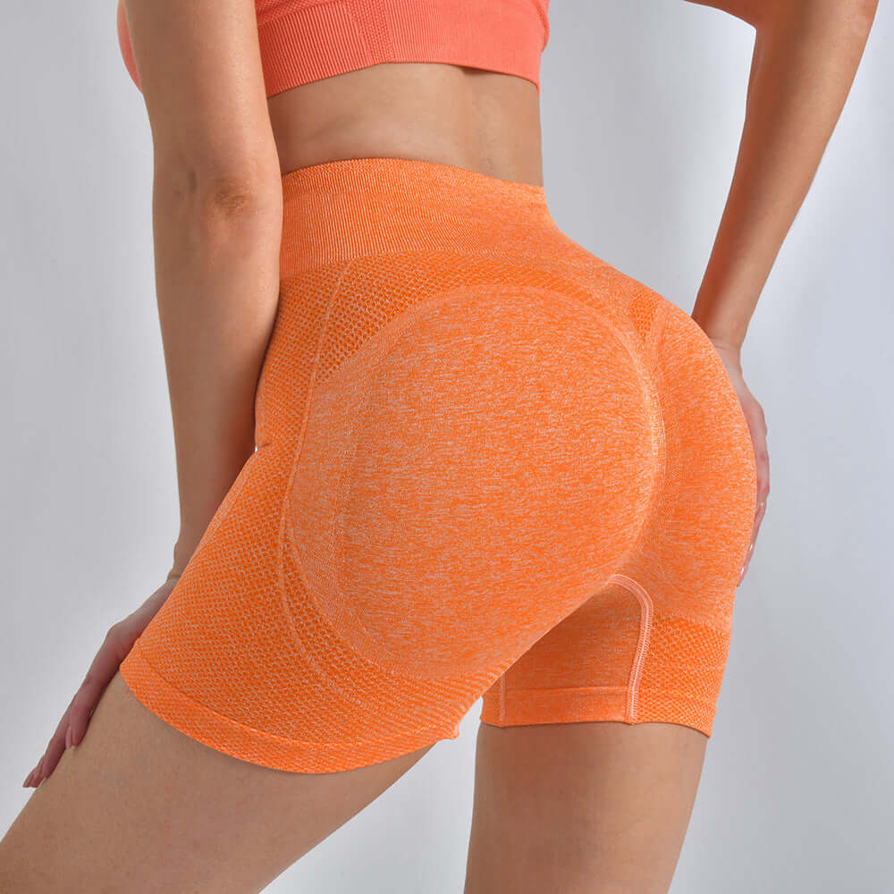 Woman wearing orange high-waist striped yoga shorts providing hip-lifting support, ideal for running and fitness, highlighting back view.