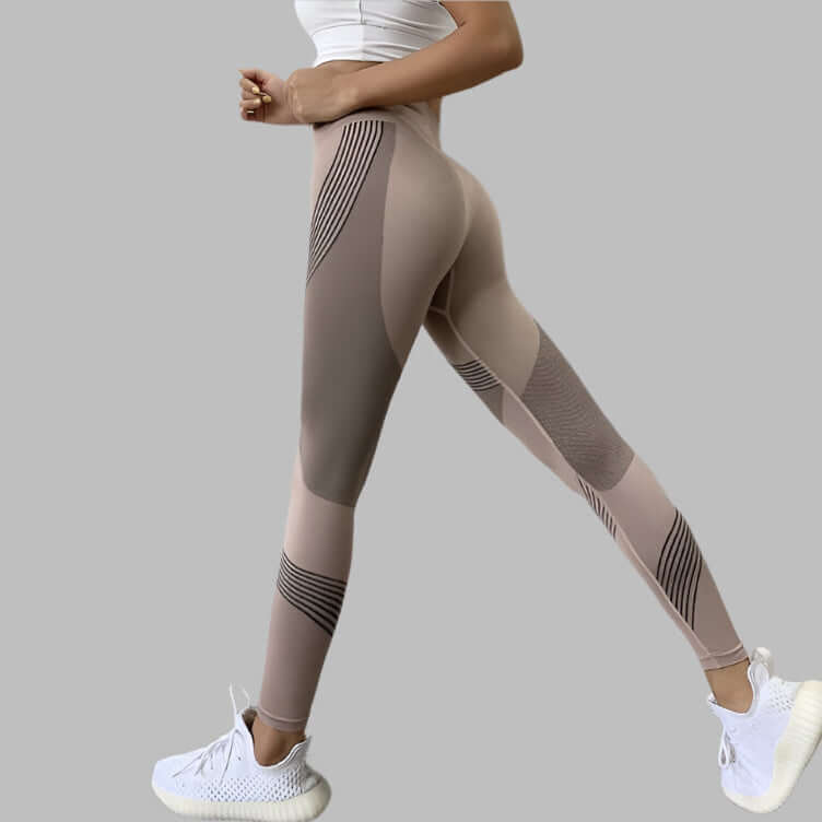 Woman wearing high waist yoga pants with stripe design and white sneakers on a gray background
