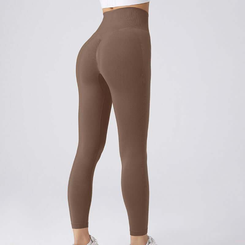Model wearing brown workout running leggings, showcasing high-waisted design. Available in sizes S, M, L. Ideal for fitness enthusiasts.