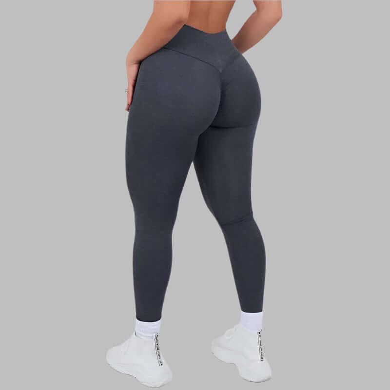 Woman wearing Sculpt Fit Scrunch Leggings in dark grey, showcasing a snug fit and design from behind against a grey background.