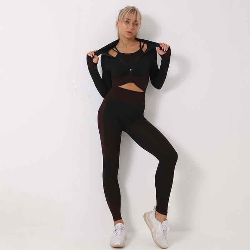 Woman wearing seamless black leggings, crop top, and sports bra with white sneakers, showcasing athletic fashion against a white background.