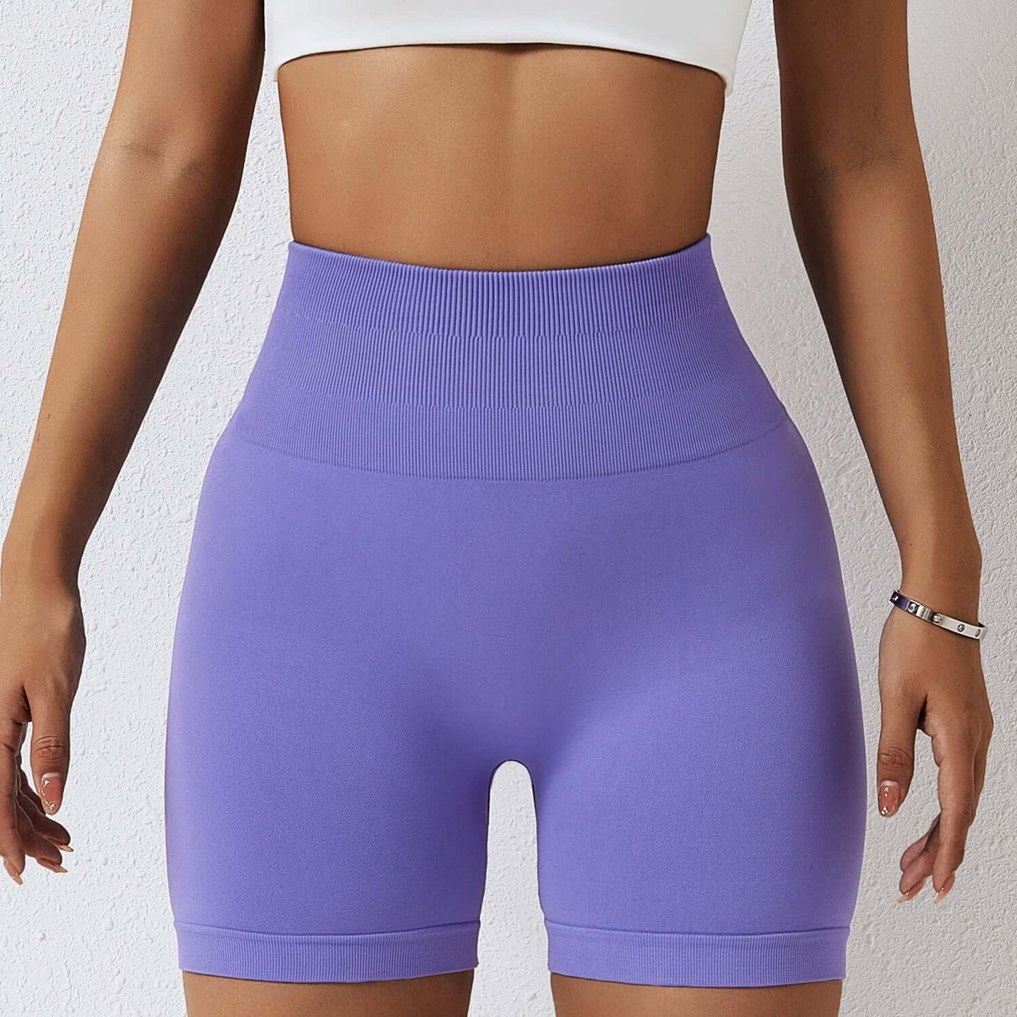 Woman wearing seamless high-waisted purple shorts with a crop top, showcasing comfortable and stylish activewear.