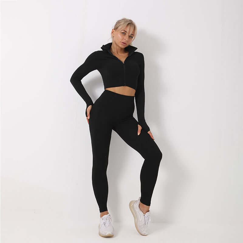 Woman wearing a black seamless leggings, crop top, and bra set, showcasing activewear fashion in a minimalist setting.