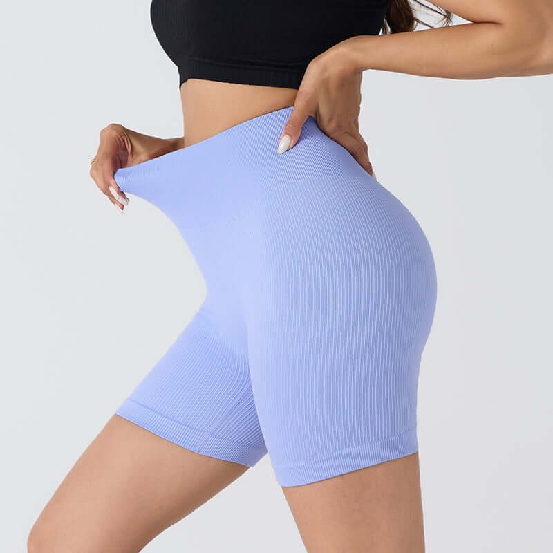 Woman wearing seamless stretch shorts in blue, showcasing flexible fit and breathable nylon fabric, ideal for fitness and casual wear.