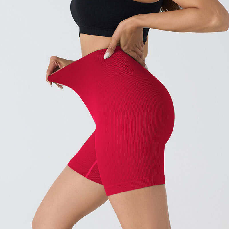 Woman wearing seamless stretch shorts in Coral Red, showcasing flexibility and form-fitting design, ideal for yoga and casual wear.