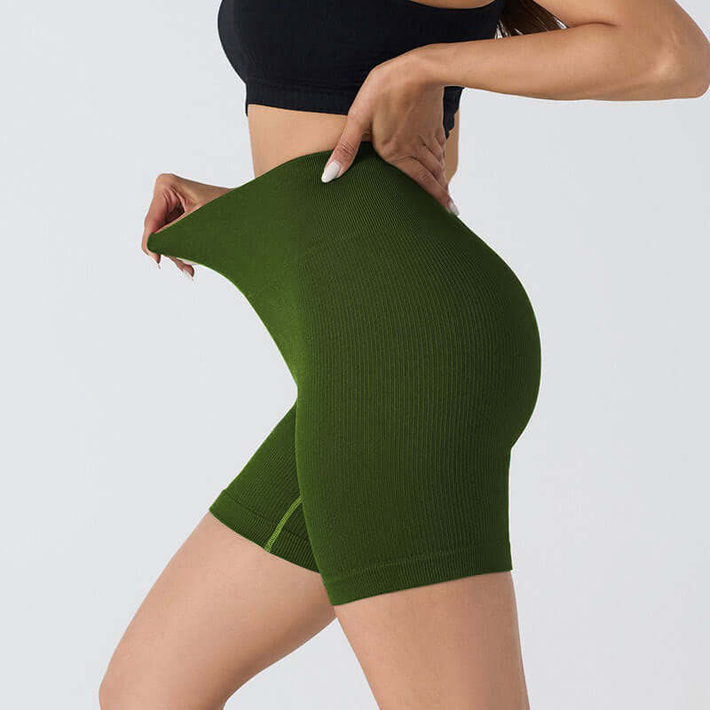 Woman wearing seamless stretch shorts in dark green, showcasing flexibility and flattering fit, ideal for yoga or casual wear.