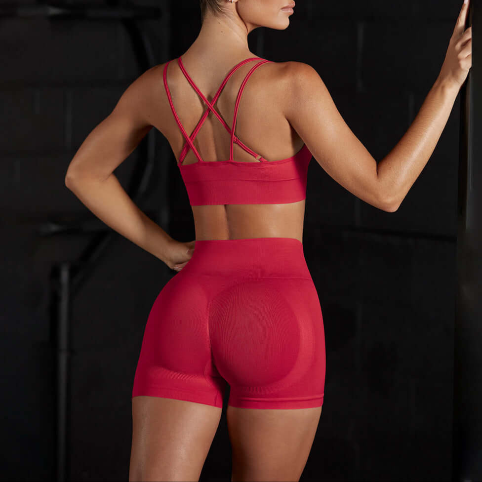 Woman in red stretch sports set with strappy back, showcasing seamless and breathable design for yoga or training. Cotton blend.