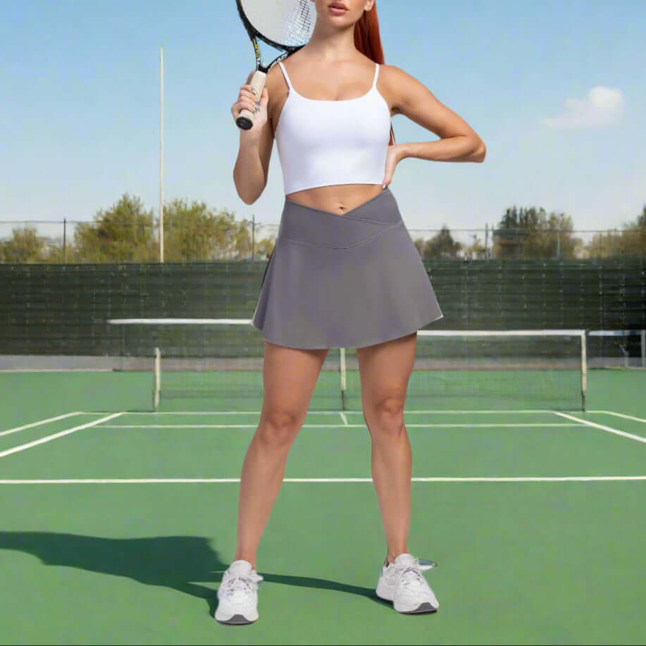Female athlete wearing sport yoga shorts with built-in skirt, holding tennis racket on court. Moisture-wicking, stylish, solid color design.