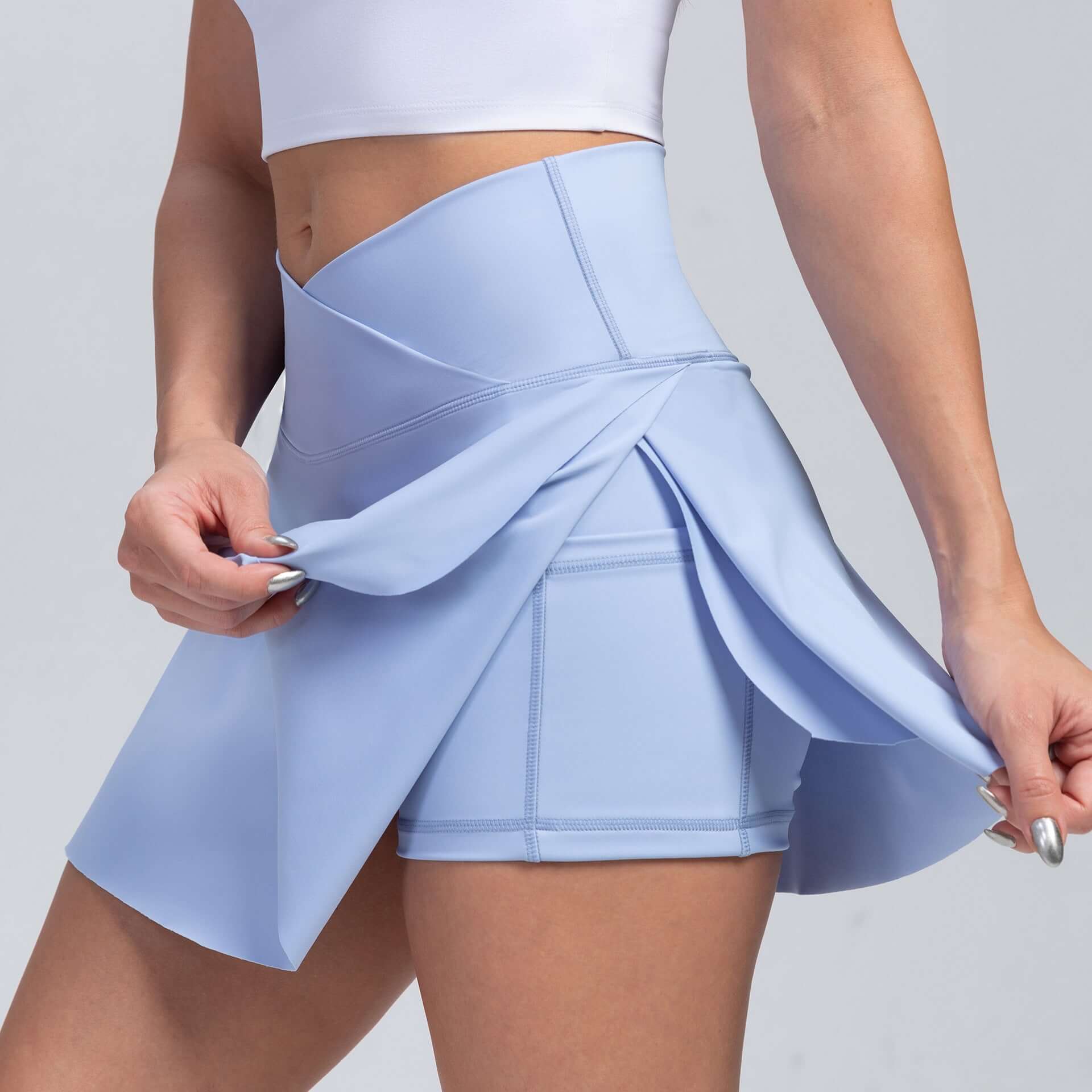Woman wearing blue sport yoga shorts with built-in skirt, designed for moisture absorption and flattering fit in all seasons.
