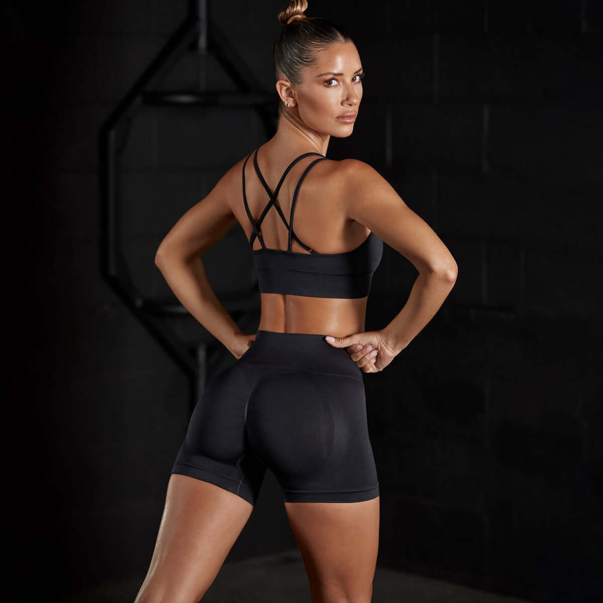 Woman wearing black stretch sports set for yoga, featuring seamless design with a stretch-fit sports vest and matching shorts in a cotton blend.