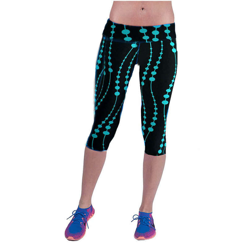 Woman wearing black yoga leggings with blue printed patterns, paired with purple sneakers.