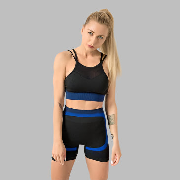 Woman wearing black and blue 2PCS gym set with shorts and sports bra.