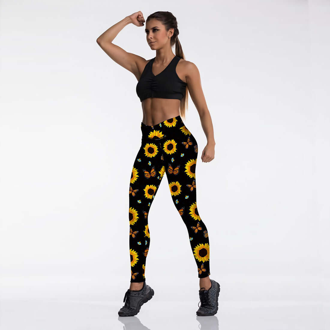 Woman wearing athletic outfit with sunflower print leggings, showcasing fitness fashion in a studio setting.