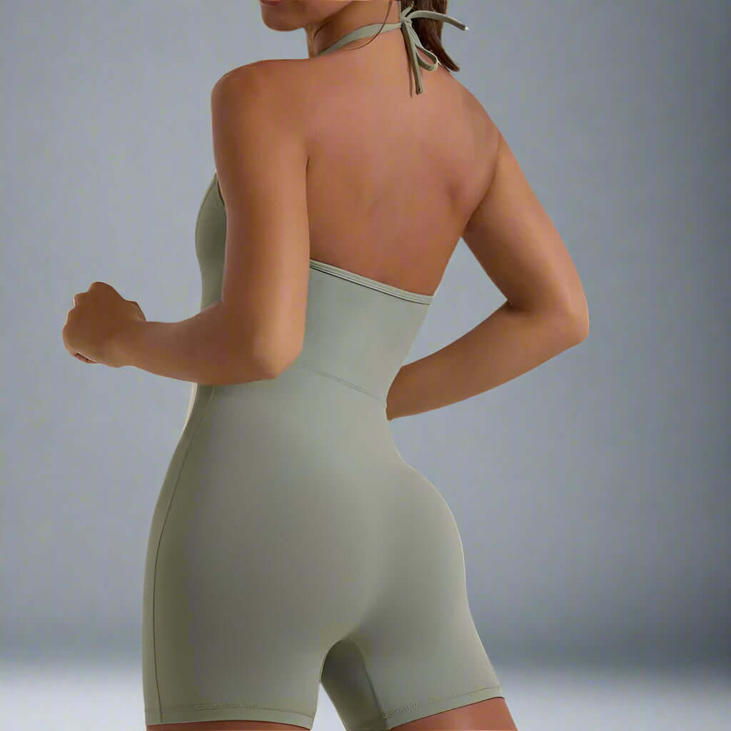 Woman wearing a form-fitting body sculpting jumpsuit in light grey, showcasing the design from the back.