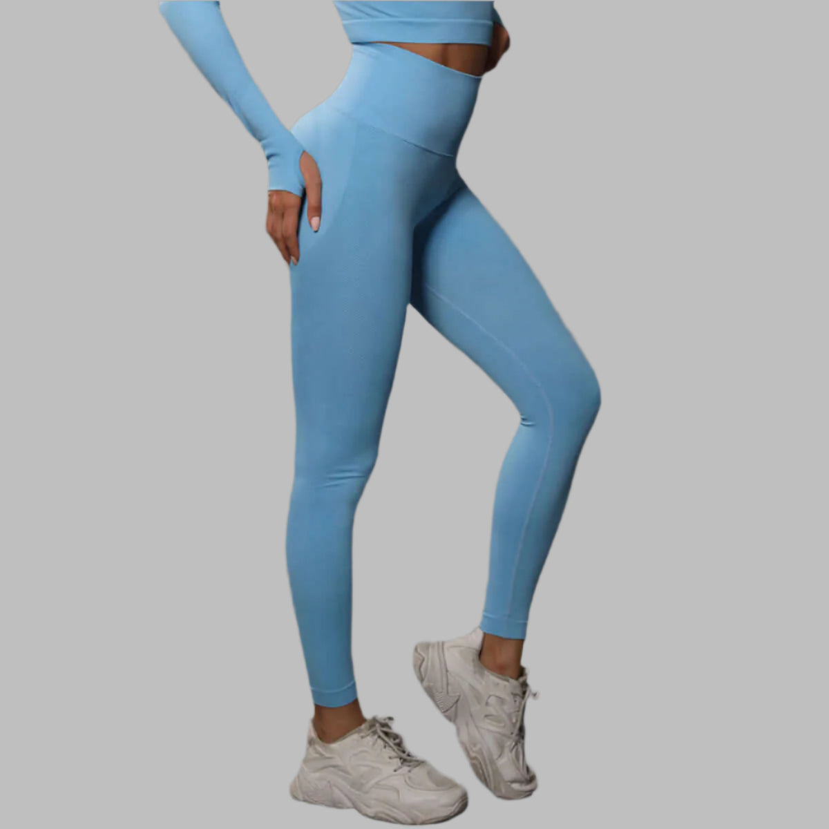 Woman wearing blue high waist leggings and matching top, showing sleek design and comfortable fit, paired with white sneakers.