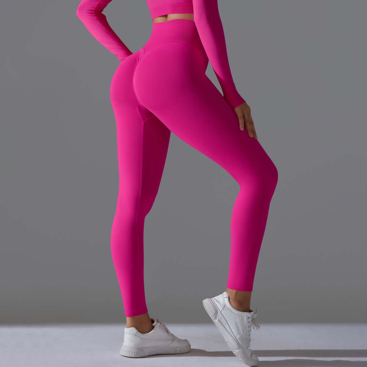 Woman wearing seamless high waist leggings in dragon fruit color, showing back view with a fitted design and white sneakers.