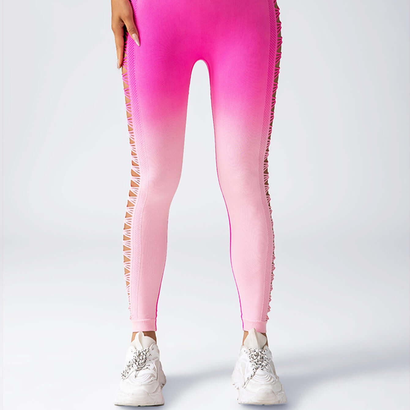 Gradient pink to white booty leggings with cut-out side details, paired with white sneakers; perfect for workouts or casual wear.