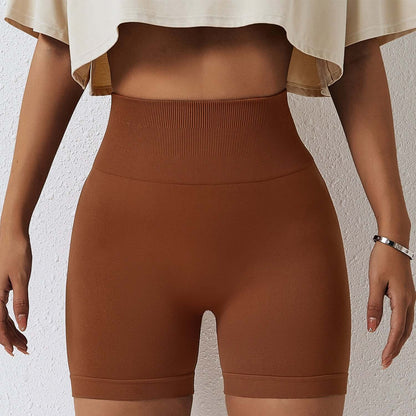 Woman wearing seamless high-waisted shorts in brown, showcasing comfortable and stylish fit. Ideal for yoga and casual wear.