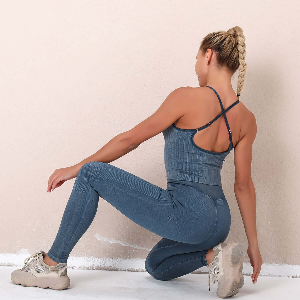 Woman wearing a blue seamless suit kneeling, showcasing the back design and fit of the activewear.