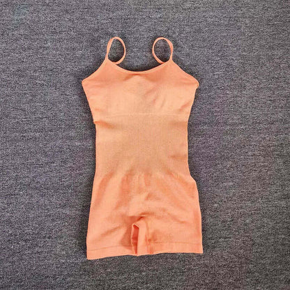 Peach seamless knit yoga jumpsuit with spaghetti straps on a gray background.