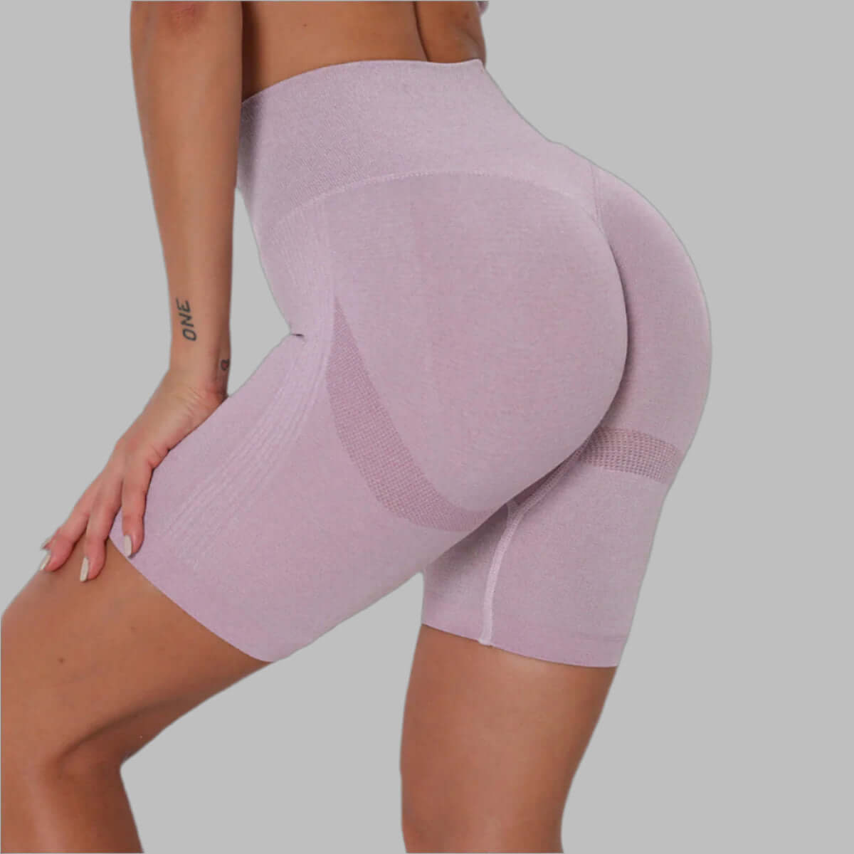 Back view of person wearing light pink high-waisted workout shorts, showcasing fit and stretch material.