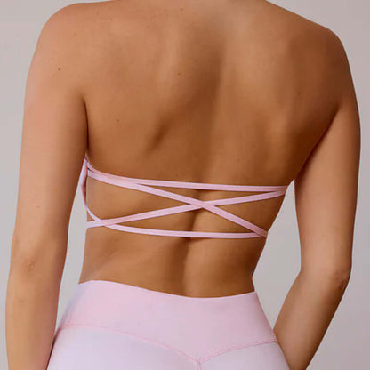 Back view of a woman wearing a pink workout beauty set with cross-strap design, showcasing stylish activewear for fitness.