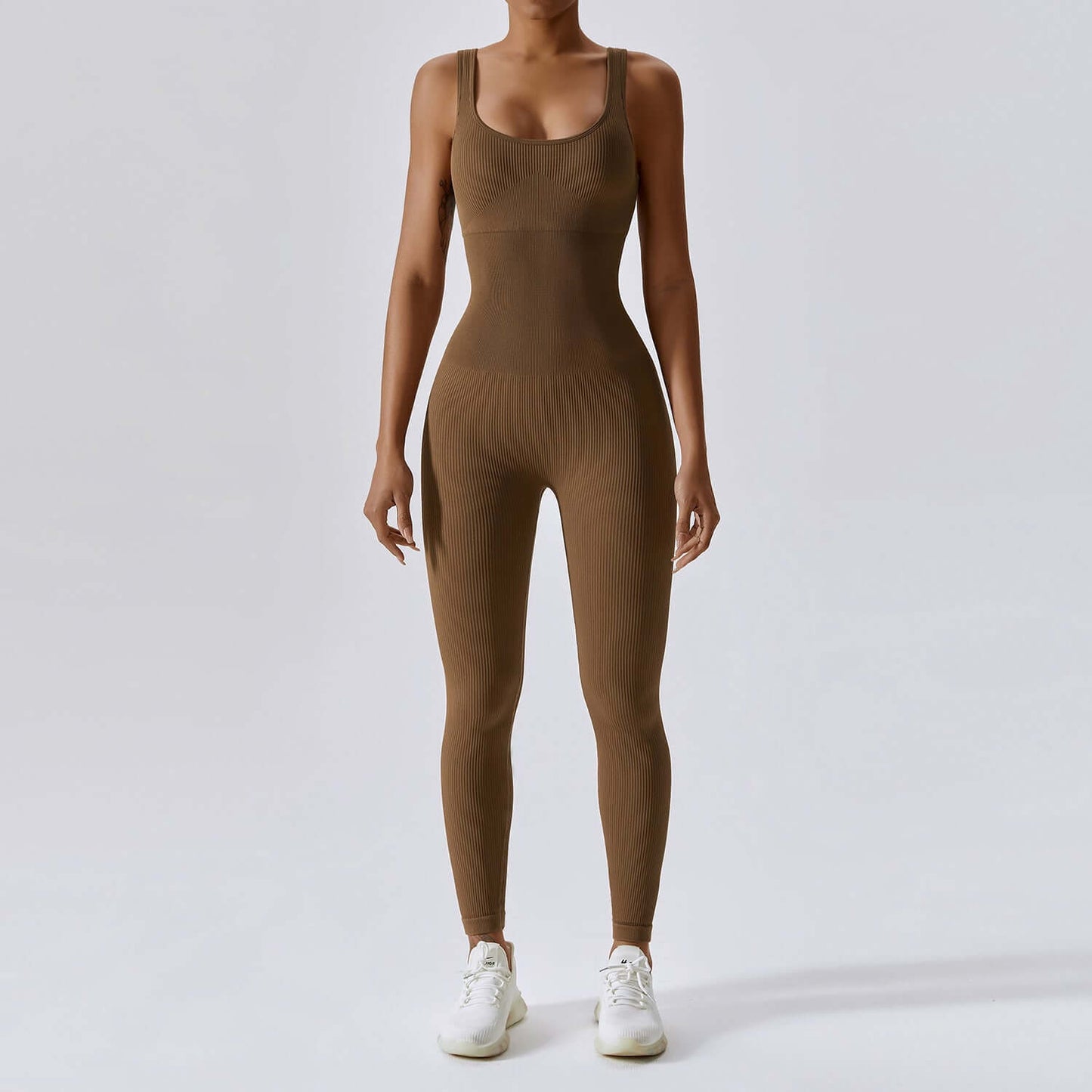 Woman wearing Sculpting Yoga Bodysuit in Coffee color, seamless sleeveless one-piece with scoop-neck and open-back, tight fit design.