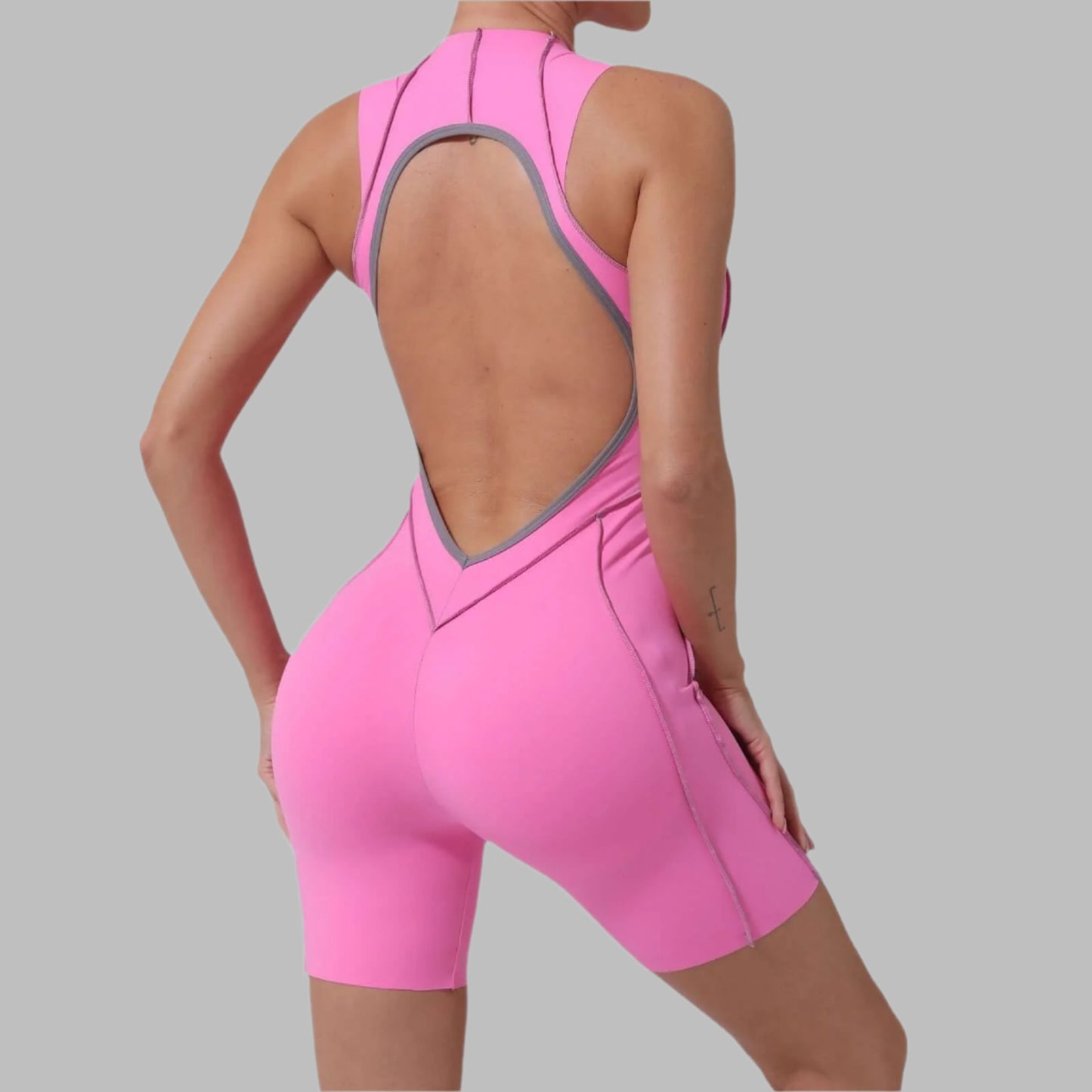 Back view of a pink all-in-one yoga jumpsuit made of organic cotton, showcasing its seamless, flexible, and breathable relaxed fit design.