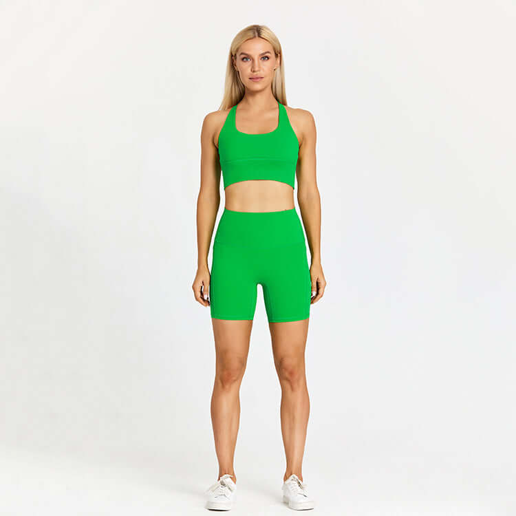 Woman in green outdoor sports set standing against white background.