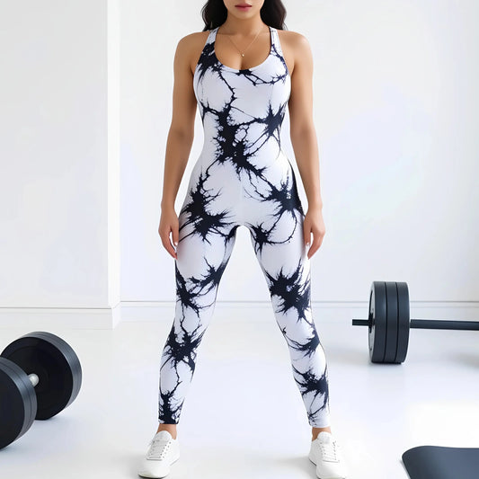 Woman wearing a black and white tie-dye compression workout bodysuit standing in a gym setting with weights on the floor.