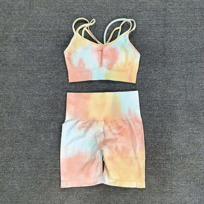 Colorful seamless sport set featuring a tie-dye sports bra and high-waisted shorts on a gray background.