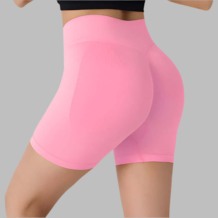 Back view of pink booty-lifting sports shorts for women, designed to enhance curves during workouts, on a gray background.