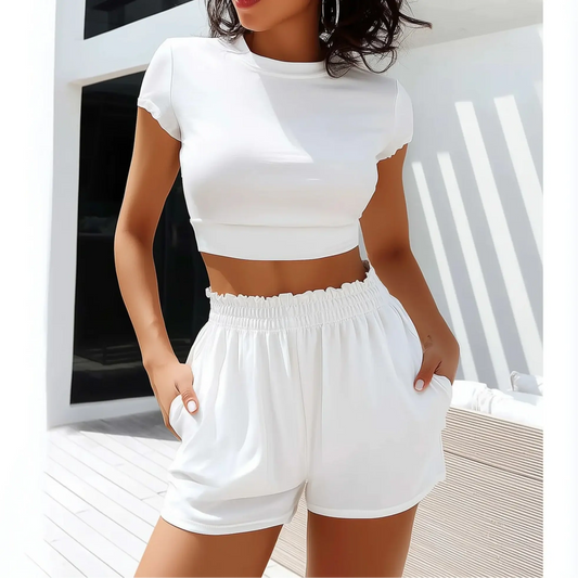 Woman wearing white casual sports suit, featuring a cropped tee and elastic waist shorts, perfect for lounging or light workouts.