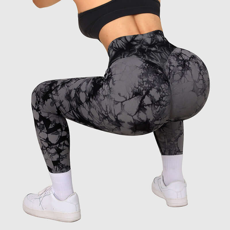 High-waisted black tie dye leggings in a squat position, showcasing stretch and fit for active wear.