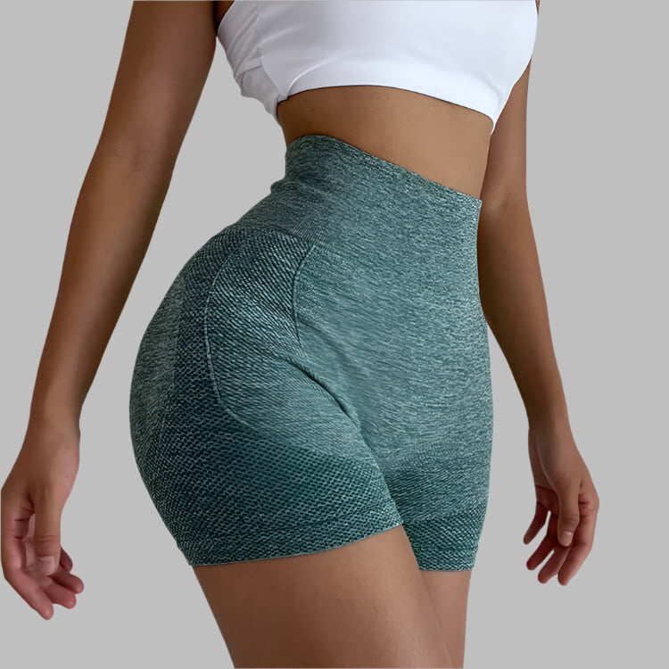 Woman wearing green seamless gym shorts with a white top, showing high-waisted design and textured fabric, ideal for workouts.