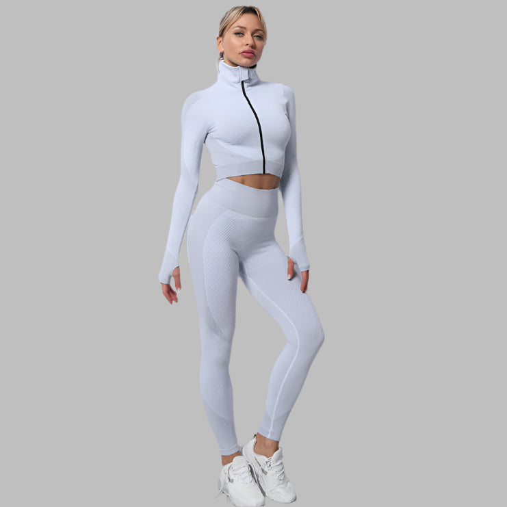 Woman wearing seamless white leggings and crop top outfit with zippered front, posing against a gray background.