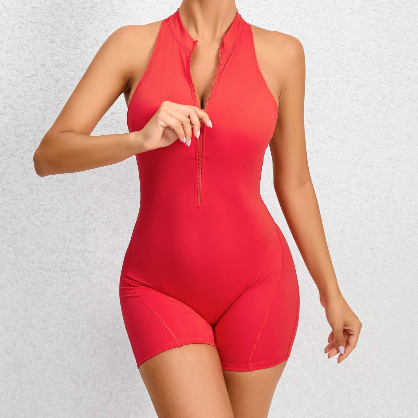 Red fitness romper, zippered front. Made from organic cotton. Breathable material, relaxed fit. Ideal for workouts and leisure.