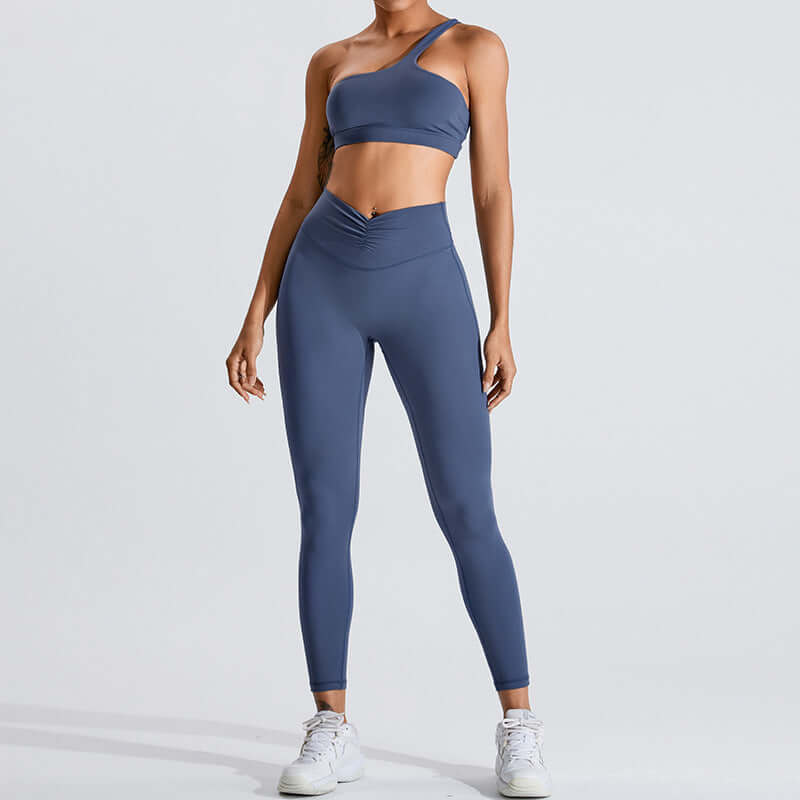 Woman wearing a stylish blue fashion yoga set with asymmetric crop top and high-waisted leggings, perfect for fitness and fashion enthusiasts.