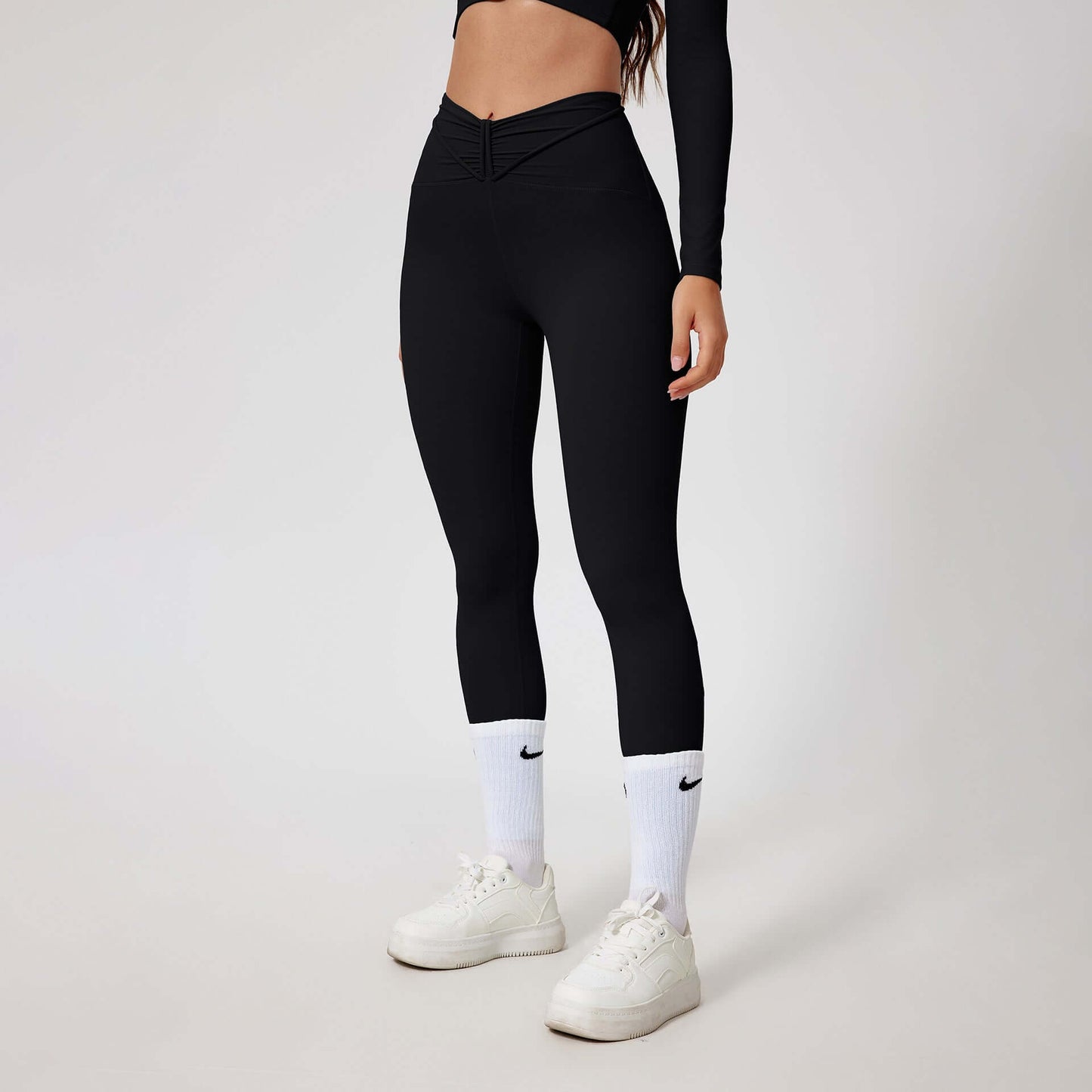 Woman wearing black seamless shaping leggings with white sneakers, showcasing a fitted and sleek activewear look.