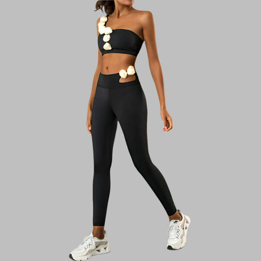 Woman wearing black high elastic workout set with floral accents, featuring strapless top and leggings, showcasing fitness style.